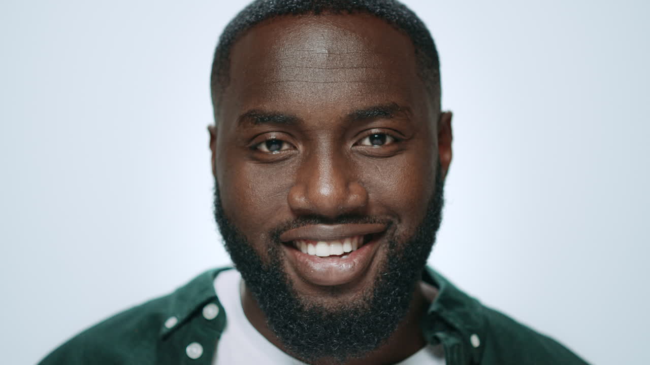 retrato de un hombre afroamericano sonriendo en un fondo gris en el estudio.