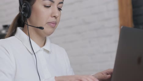 woman call centre operator, customer support agent wears headset consults client online, typing on laptop, talk in internet computer chat, helpline operator secretary make conference video call