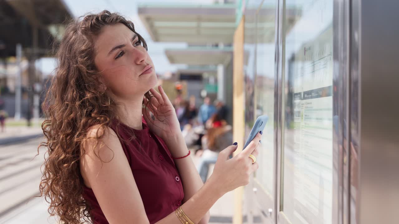 Mujer joven consultando el horario en el teléfono en una parada de transporte público