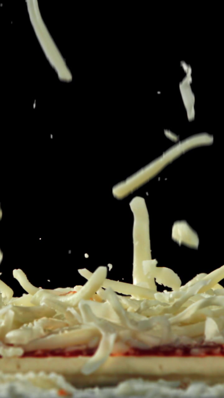 Shredded Mozzarella Cheese Falling onto a Pizza Base in Slow Motion