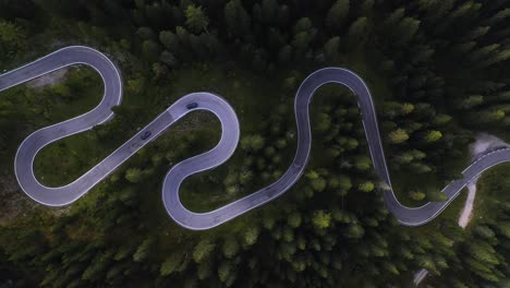 aerial view rising above traffic on a serpentine road, in sunny dolomites, italy