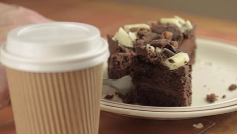 comiendo pastel de chocolate con tenedor y sacando café plano medio