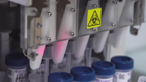 close-up in the medical laboratory, the robot pierces a jar of liquid with a needle and pours it into a tube for further analysis by the doctor