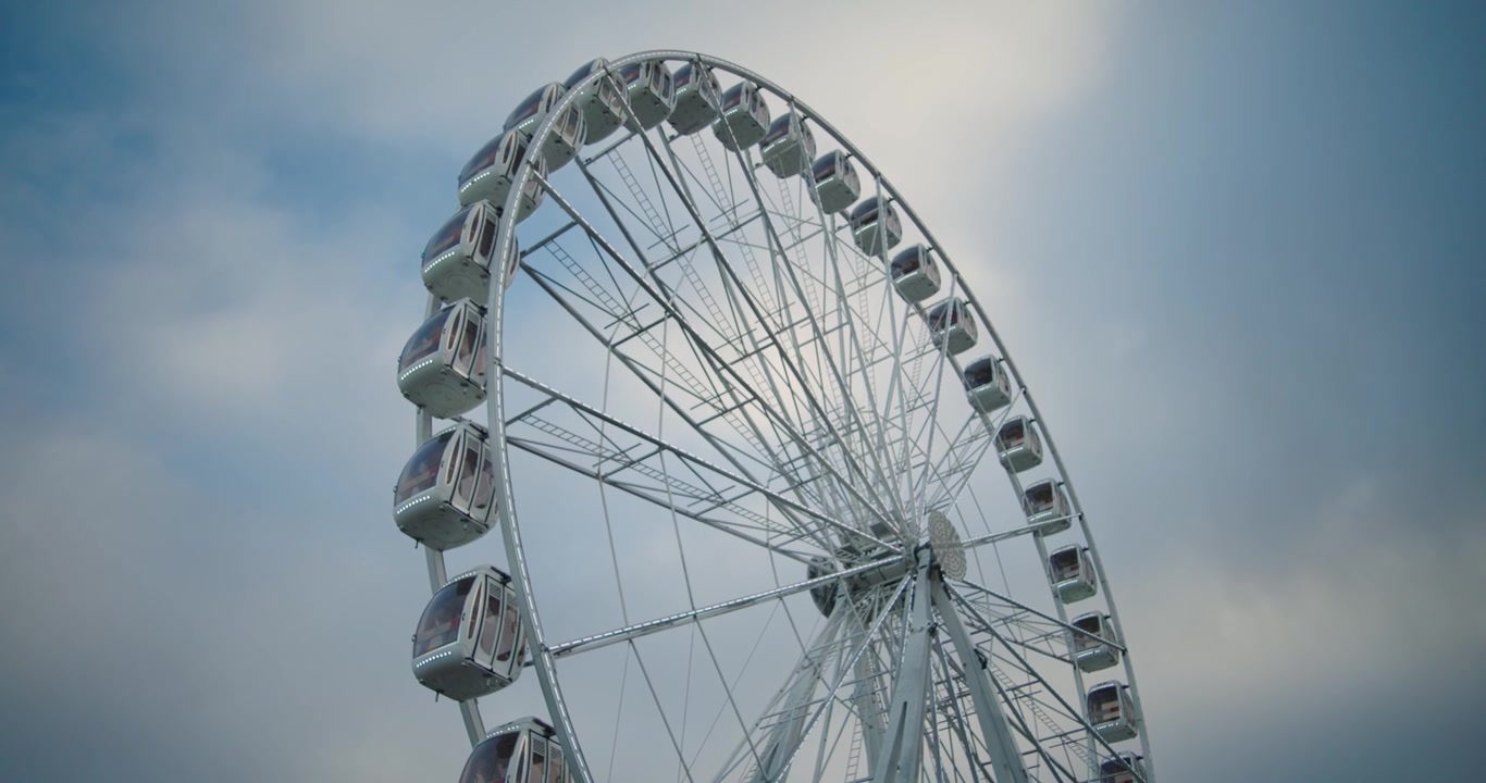 4K filmatisk opptak av et pariserhjul som roterer sakte mot en blå skumringshimmel. En fredelig fornøyelsesparkscene med forsiktig bevegelse og kveldsstemning.