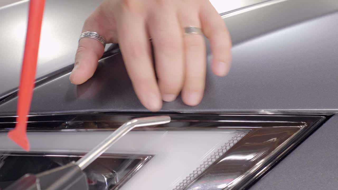 envoltura de coche con pistola de calor, aplicación cuidadosa de papel de vinilo en el capó, primer plano