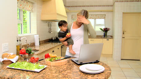 Busy-woman-holding-baby-while-phoning-and-working-on-laptop