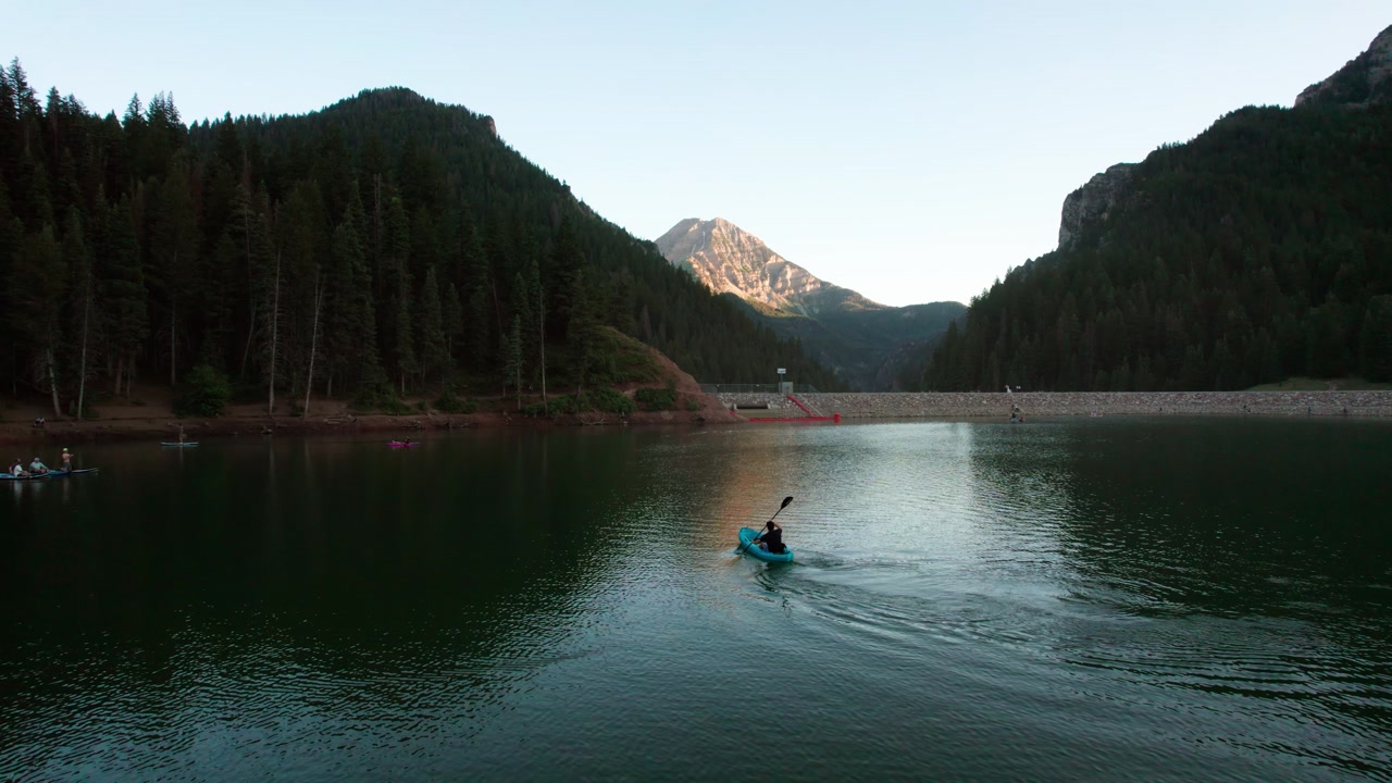 A Kayaker Glides Across Tibble Fork Reservoir Surrounded by Mountains in Utah, USA - Orbit Drone Shot