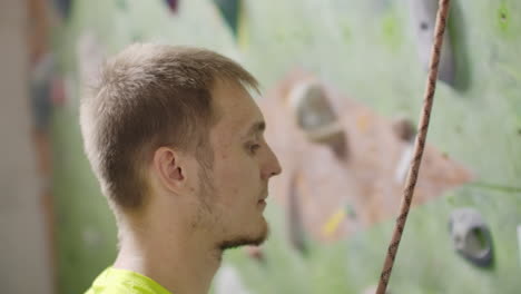 portrait of a climber preparing to climb the wall in the hall to chalk his hands and climb the wall with insurance in slow motion.