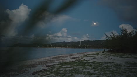 fotografía de la playa de la tarde con la luna apareciendo