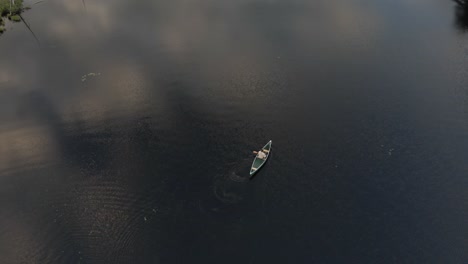 Vista-De-Pájaro-De-Un-Hombre-En-Una-Canoa-Navegando-En-El-Lago-Claro