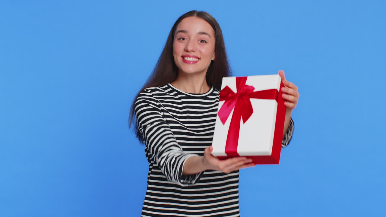 Smiling young woman presenting birthday gift present box stretches out hands promotion discount sale