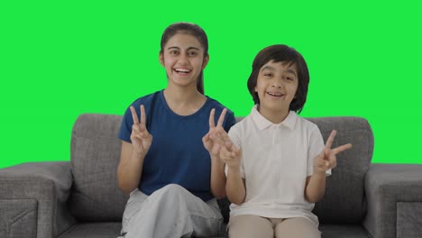 hermanos indios felices mostrando el signo de la victoria a la cámara pantalla verde
