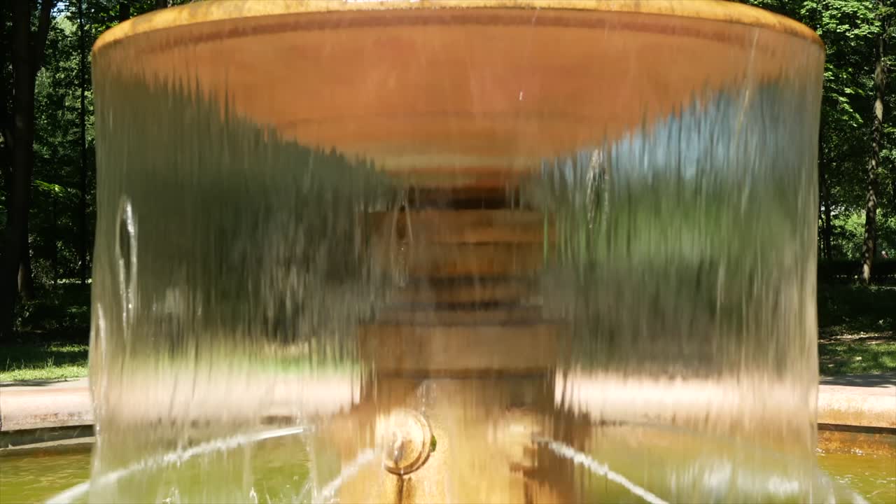 A small fountain with water in the summer park - a place of rest from the heat