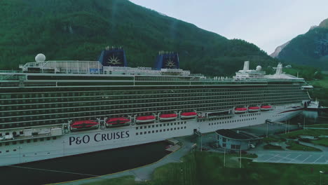 Massive-cruise-ship-moored-at-Flam-township-in-Norway,-aerial-view