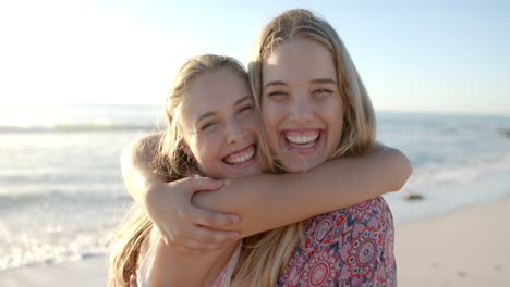 two young caucasian women embrace joyfully on a sunny beach