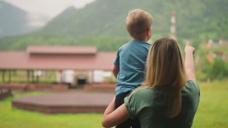 woman holds little son showing distant mountains in hotel