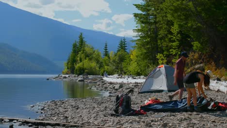 Hiker-couple-preparing-tent-near-riverside-4k