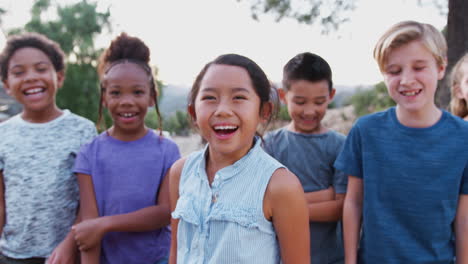 portrait of multi-cultural children hanging out with laughing friends in countryside together