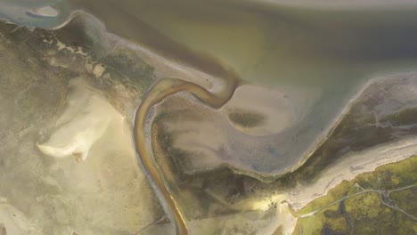 birdseye drone view with patterns of water and sand at sea in wadden island texel, netherlands ascending orbit