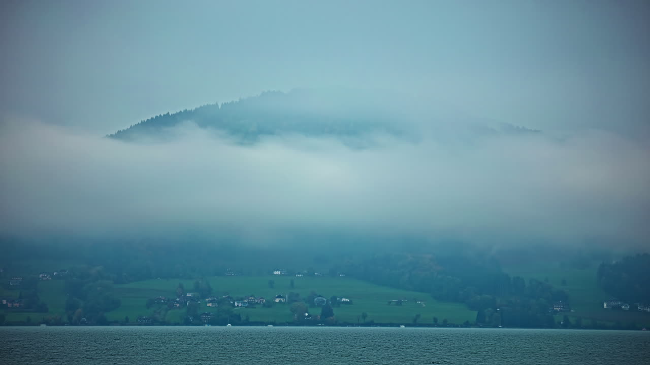 오스트리아 상부 오스트리아 주 살츠카메르구트 (salzkammergut) 에 있는 아터시 호수 (attersee) 연안의 안개 구름에 싸인 산악 마을.