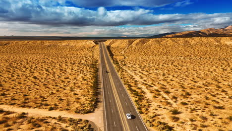 drone moving above the four-lane highway in the dry desert. arid landscape in california. dramatic cloudscape in the sky at backdrop. top view.