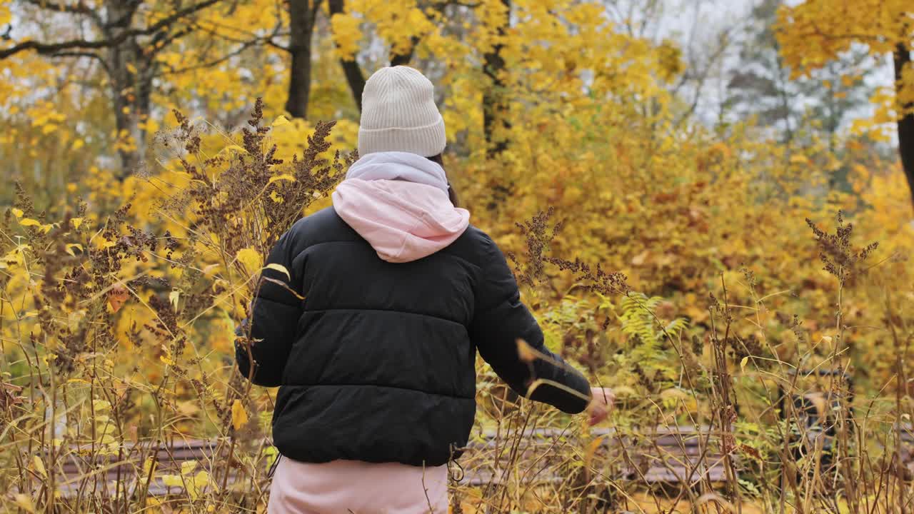 A peaceful autumn scene of a woman picking dried flowers in a golden forest - 4K