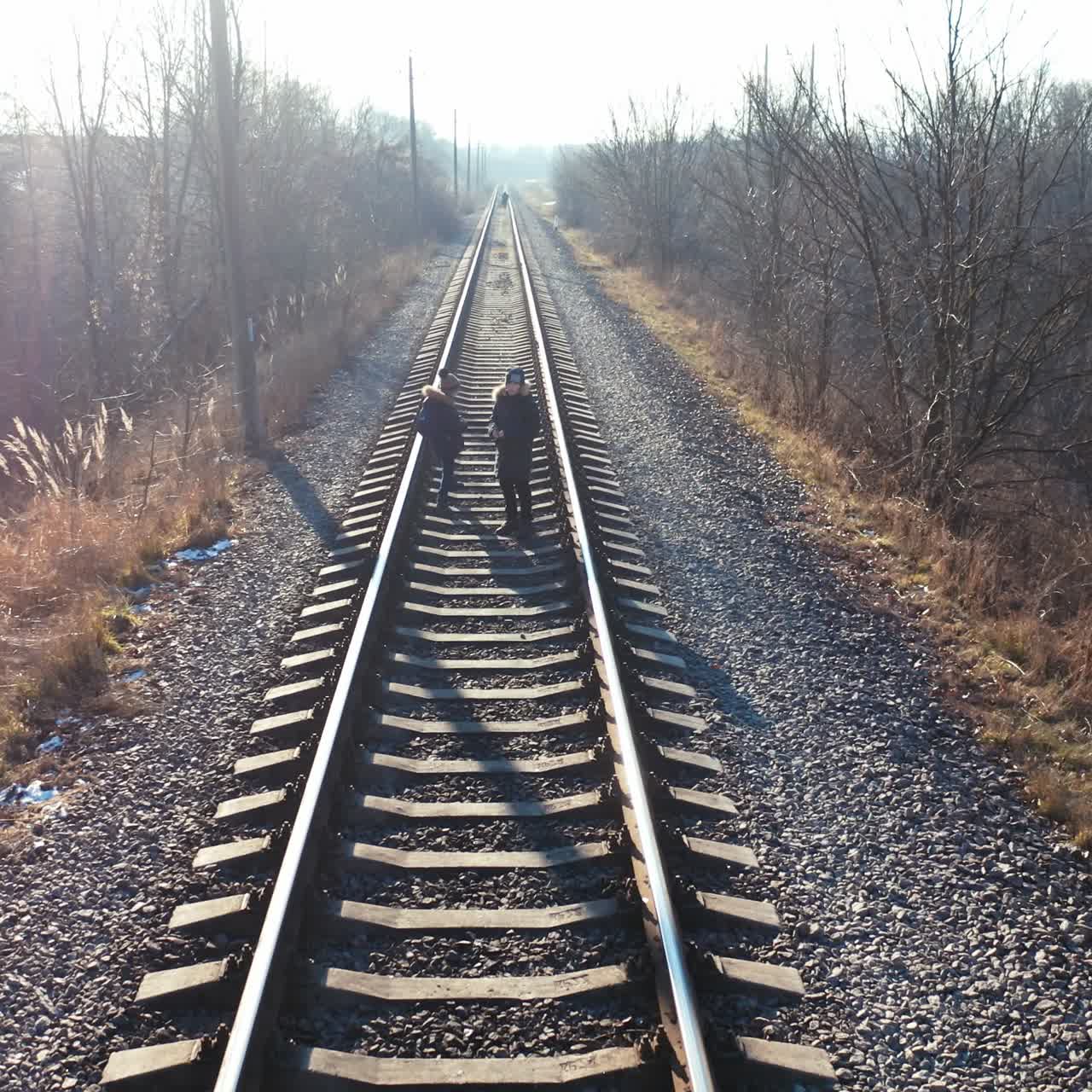 Rear view of people walking on rails