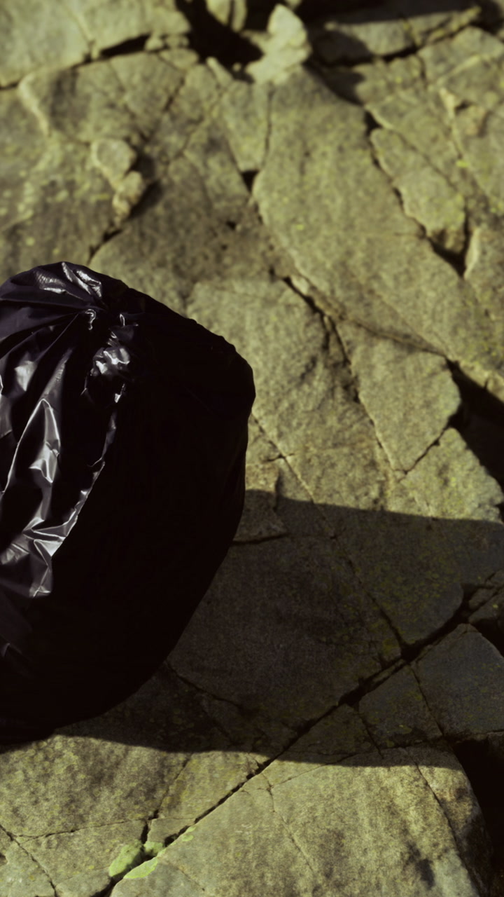 Black bag placed on cracked stone surface in natural setting during daylight