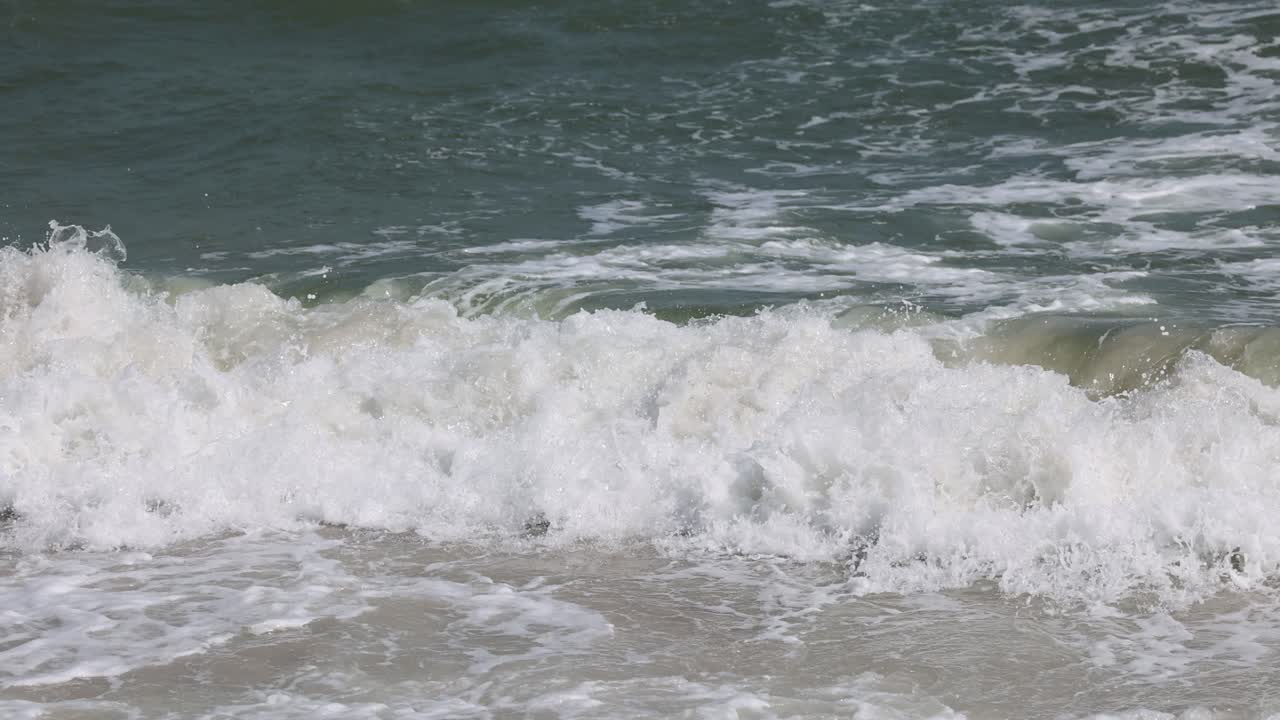 모래 해변 에서 연속적 인 파도 가 깨지는 것