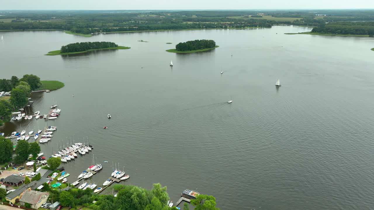 Aerial view of a lake with docked boats and small islands in the distance, surrounded by nature - Siemiany, Jeziorak lake