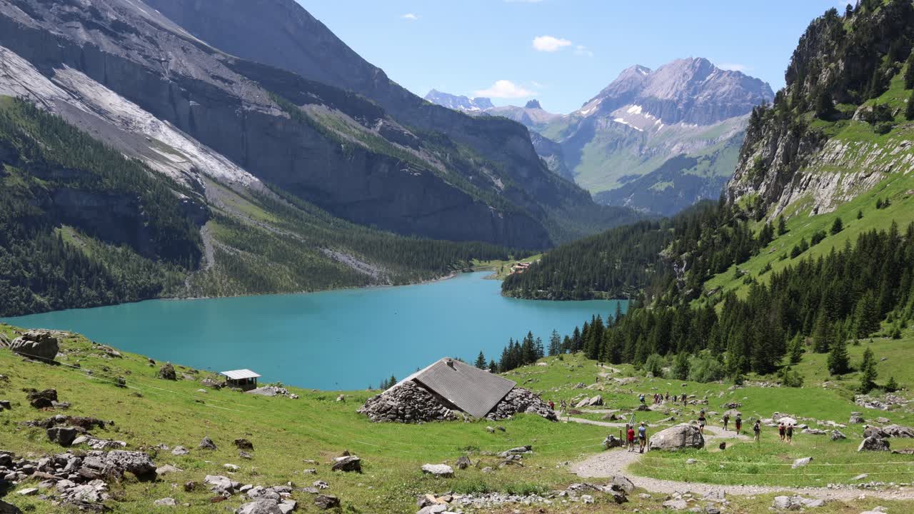People hiking in Swiss alps by the mountain lake, Oeschinensee establisher