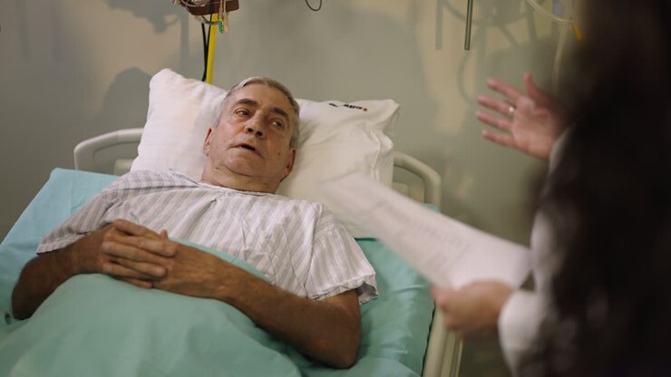 Senior man in hospital bed talking to doctor