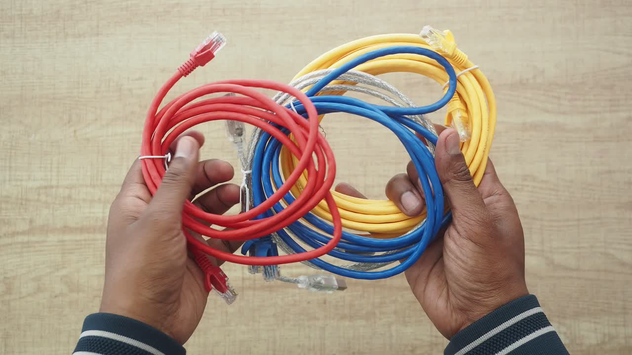 Hands holding a bundle of colorful ethernet cables