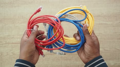 hands holding a bundle of colorful ethernet cables