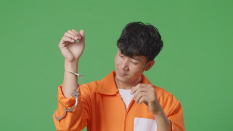녹색 스크린 배경에 서서 축하하는 골을 비명을 지르며 손이 부러진 아시아 남성 죄수