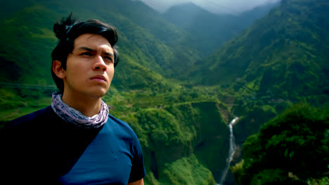 Panning-portrait-of-young-man-by-green-hills-and-waterfall-in-Ecuador