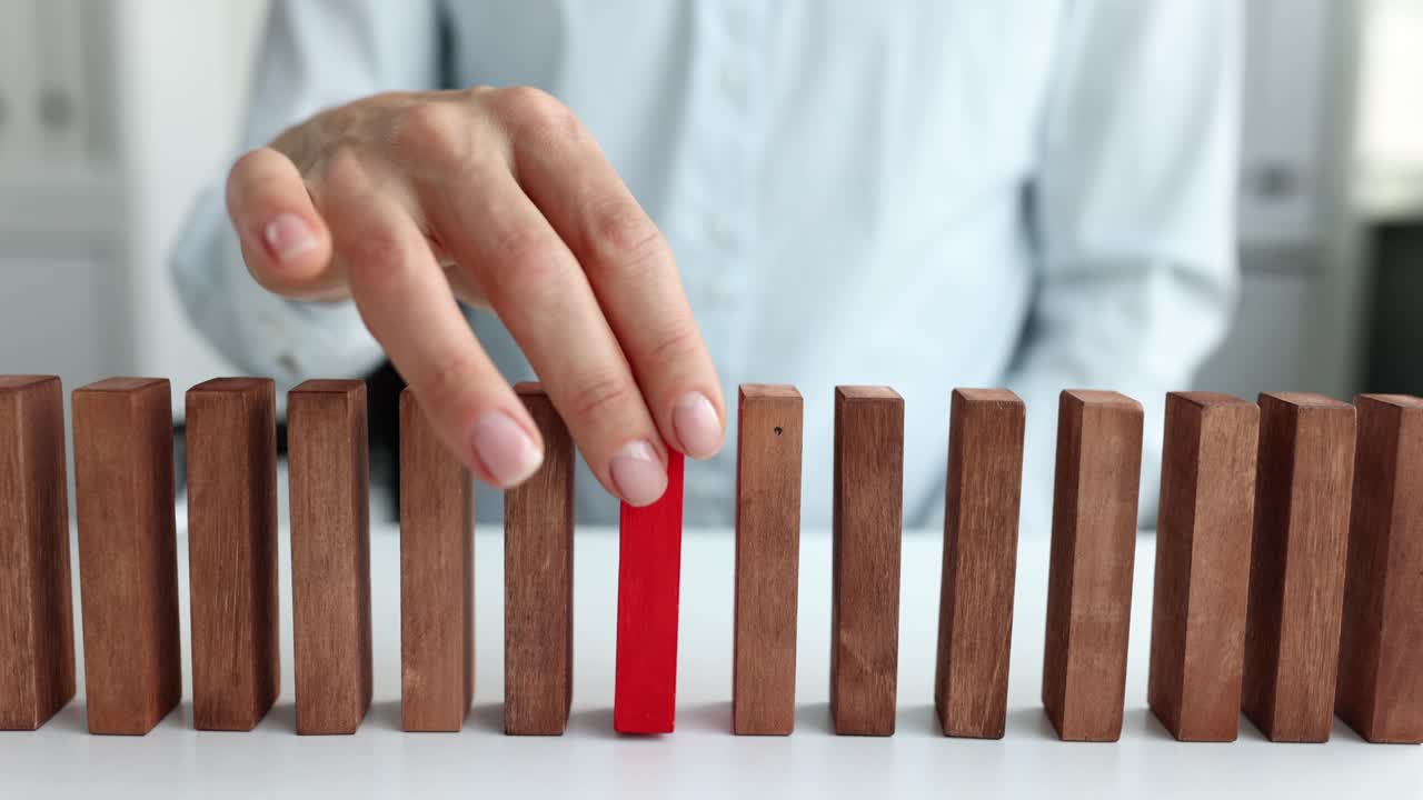 Una mano femminile seleziona un blocco rosso da una fila di blocchi di legno beige