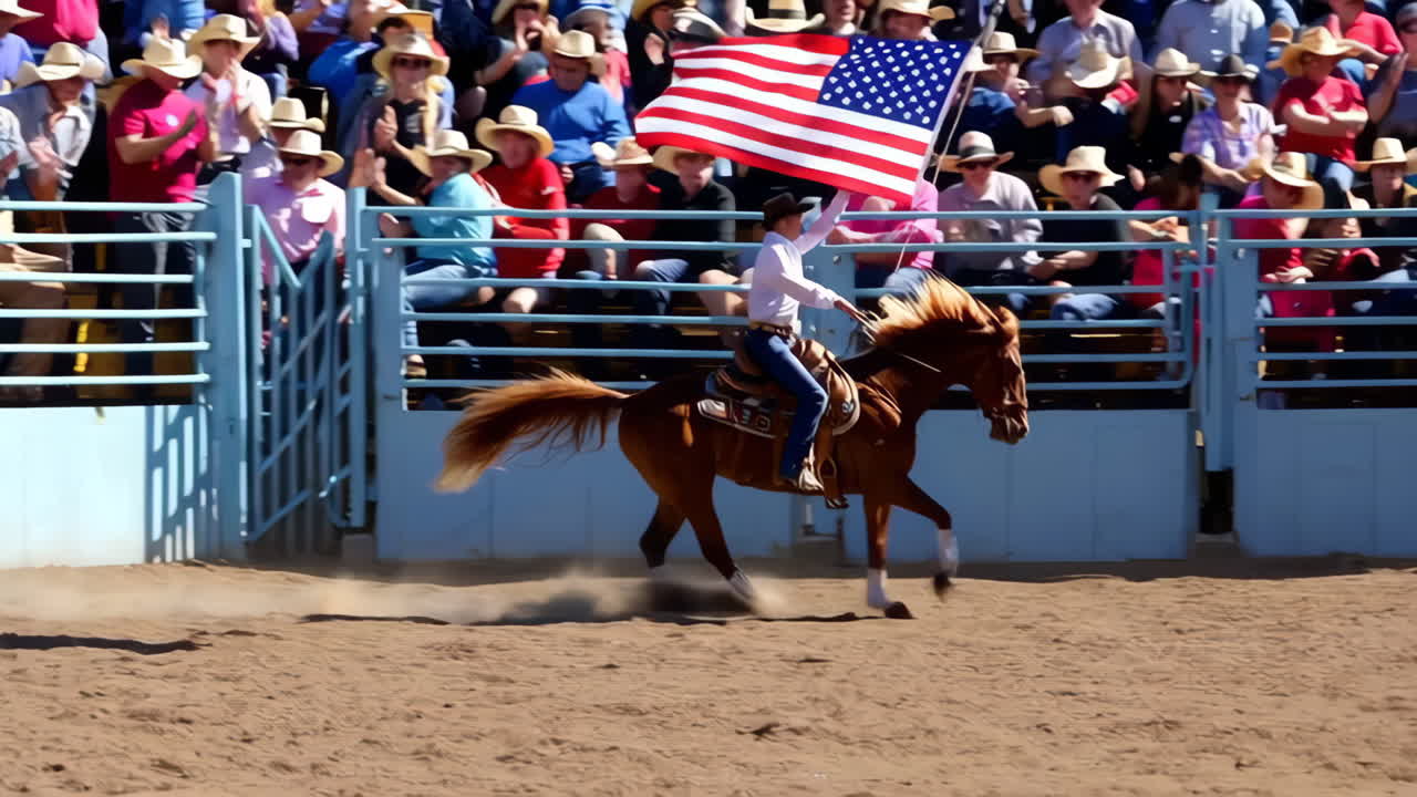 A rider on horseback carries the American flag in a rodeo arena