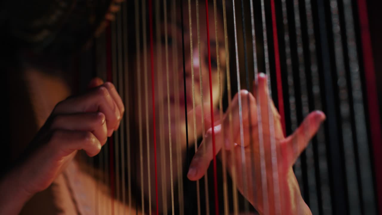 Cinematic close up shot of professional female harpist is playing harp solo on a classic theater stage with dramatic lighting