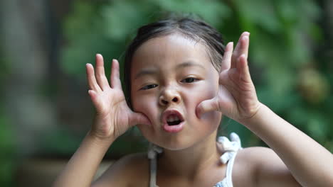 retrato de niña asiática haciendo muecas a la cámara, burlándose o burlándose de cerca