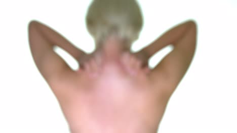 Una-Mujer-Frotando-Y-Masajeando-La-Parte-Posterior-De-Su-Cuello,-Con-Un-Efecto-De-Desenfoque-Gaussiano,-Sobre-Un-Fondo-De-Estudio-Blanco-Sin-Costuras