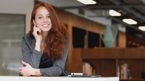 portrait of casually dressed young businesswoman standing in modern open plan workplace