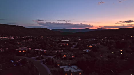 cinematic twilight drone shot of sedona arizona rising with lights on in homes