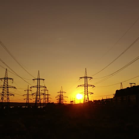 electric power station in the evening. high voltage electric lines against the setting sun. transmission lines. motion camera back.
