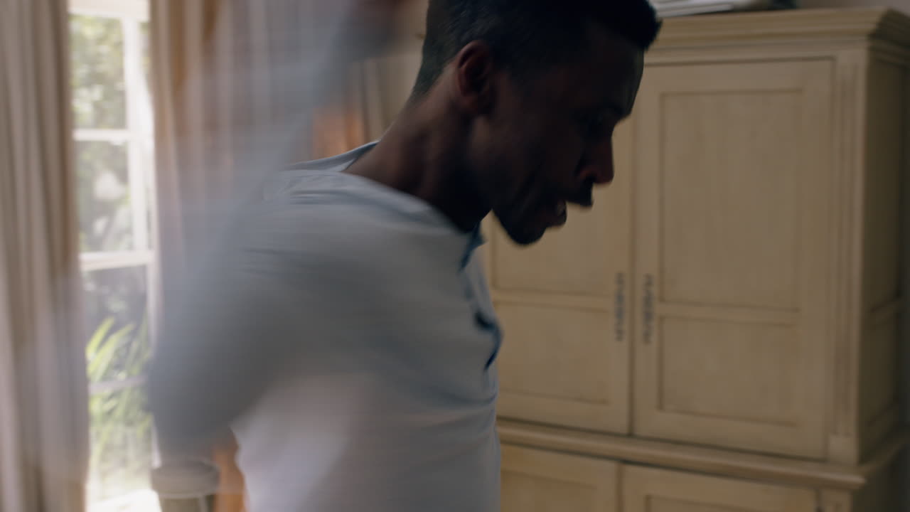 uomo afroamericano divertente che balla in camera da letto che si diverte a festeggiare sentendosi positivo che gode di uno stile di vita di successo che balla sciocchi a casa la mattina del fine settimana indossando il pigiama