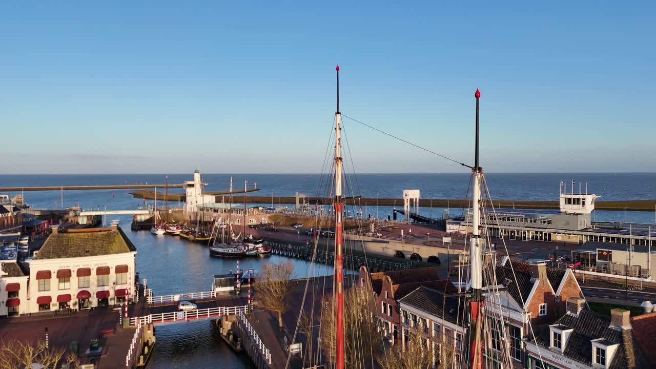 Stabil luftoptagelse i masthøjde med brotrafik, riglinjer og havnebaggrund