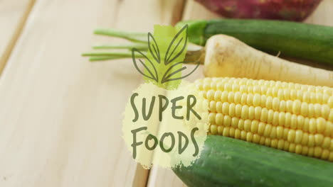 super foods text animation over fresh vegetables on wooden surface