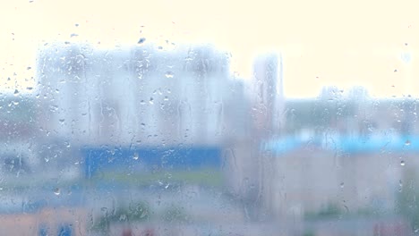 raindrops flow down the window close-up. view of multi-building house from wet window, blur