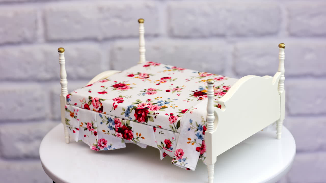 Lovely white bed with beautiful colorful bedding on. Spinning piece of furniture at white background. Close up.