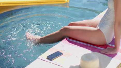 a teenage girl is dipping her feet in a pool, creating ripples in the water